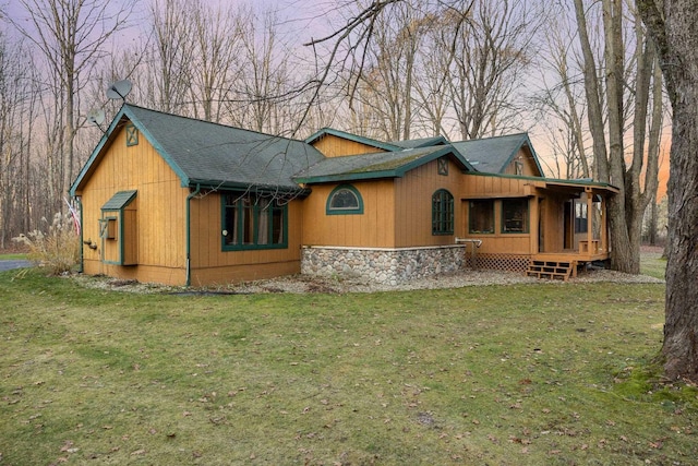 back of house with roof with shingles and a yard