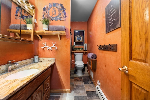 bathroom with toilet, vanity, baseboards, a baseboard heating unit, and stone finish floors