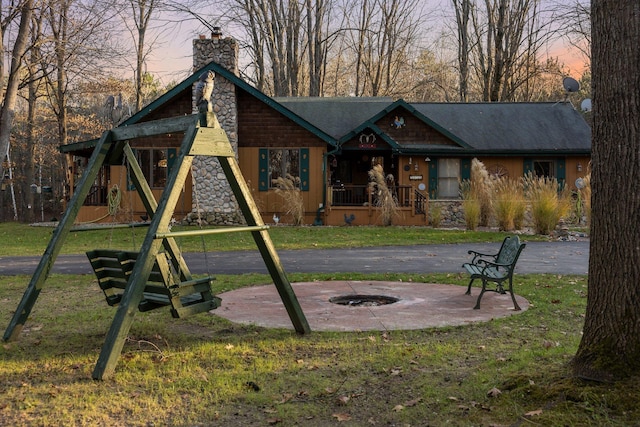 view of front of house featuring a chimney, a yard, roof with shingles, and stone siding