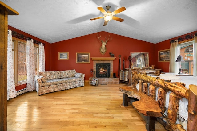 living area with ceiling fan, baseboard heating, wood finished floors, a fireplace, and lofted ceiling