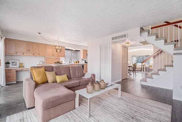living room featuring dark wood-type flooring, stairway, a textured ceiling, baseboards, and a chandelier