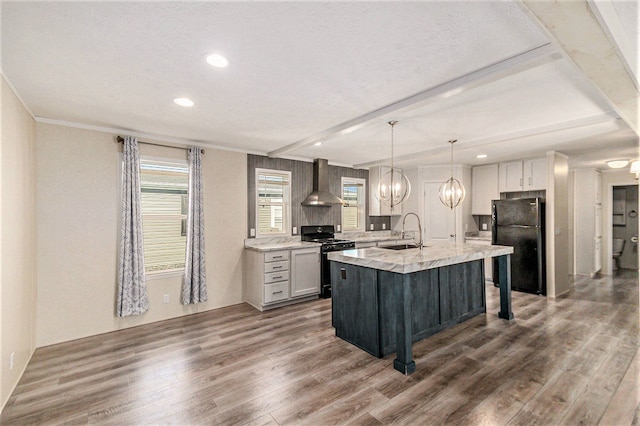 13780 Alaska Ave, Eagle, MI 48822 - kitchen with gas range oven, wall chimney range hood, freestanding refrigerator, dark wood-style flooring, and a center island with sink