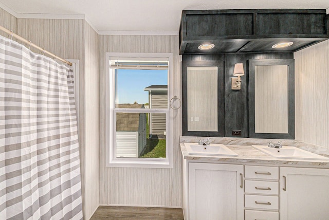 13780 Alaska Ave, Eagle, MI 48822 - bathroom featuring wood finished floors, double vanity, ornamental molding, and wallpapered walls