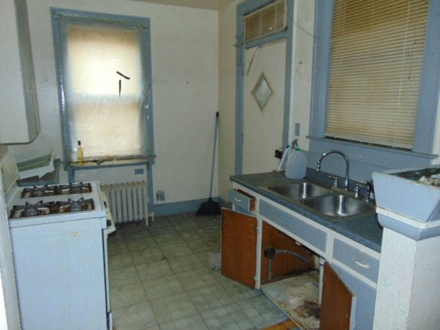 50 Glendale St, Highland Park, MI 48203 - kitchen featuring white range with gas stovetop, a sink, radiator, and light flooring