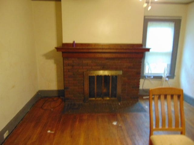 50 Glendale St, Highland Park, MI 48203 - unfurnished living room featuring a fireplace, healthy amount of natural light, wood finished floors, and baseboards