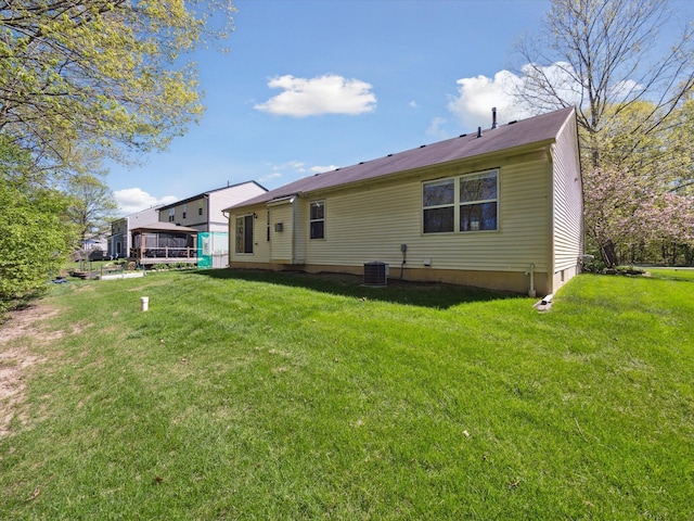 rear view of property featuring central AC and a yard