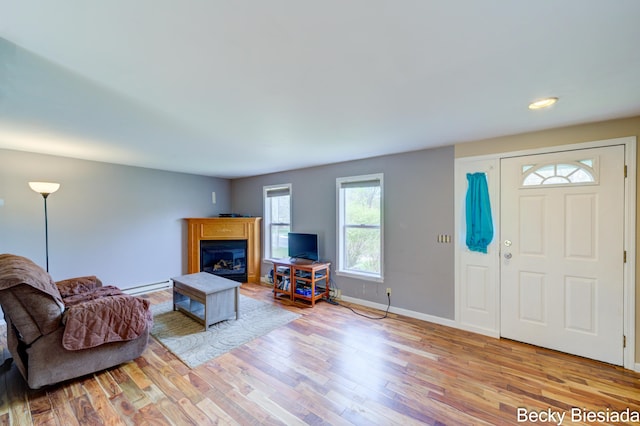 823 Warner St, Whitehall, MI 49461 - living area with a baseboard heating unit, wood finished floors, a glass covered fireplace, baseboards, and recessed lighting