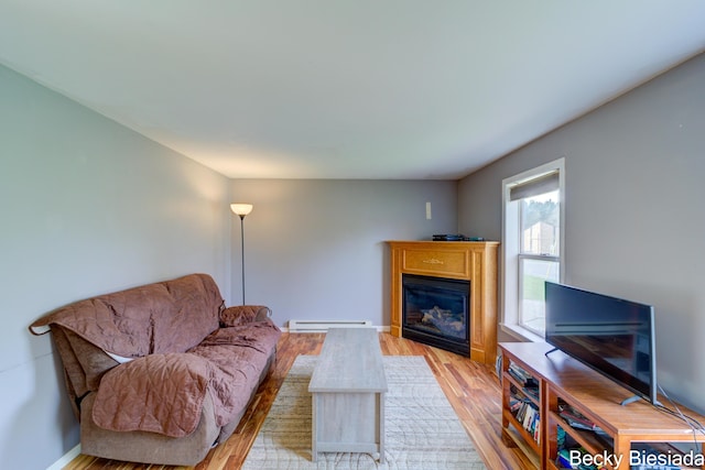 823 Warner St, Whitehall, MI 49461 - living area featuring a baseboard heating unit, light wood-type flooring, a glass covered fireplace, and baseboards