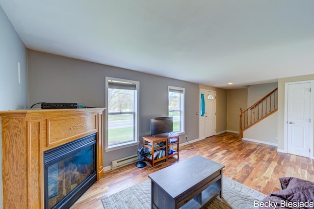823 Warner St, Whitehall, MI 49461 - living area with light wood-type flooring, stairway, a glass covered fireplace, baseboards, and a baseboard heating unit