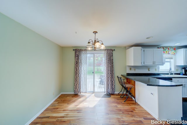 823 Warner St, Whitehall, MI 49461 - kitchen featuring a chandelier, light wood-type flooring, white cabinets, dark countertops, and recessed lighting