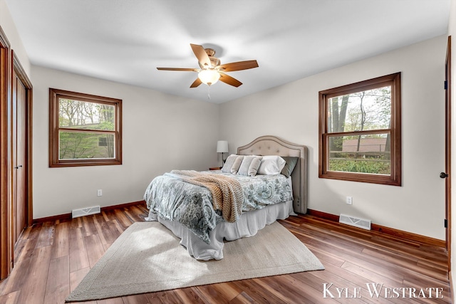 bedroom featuring multiple windows, baseboards, and wood finished floors