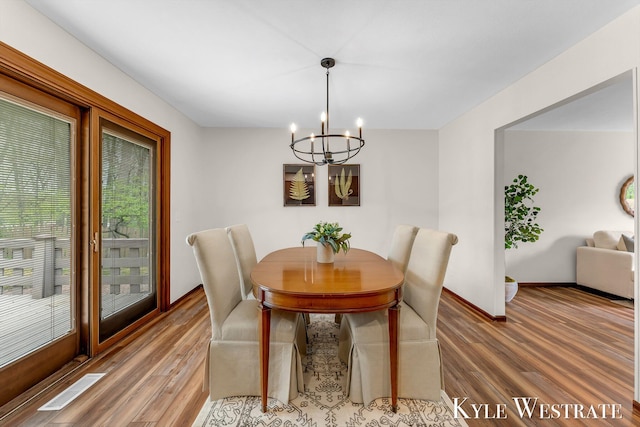 dining space with a chandelier, wood finished floors, and baseboards
