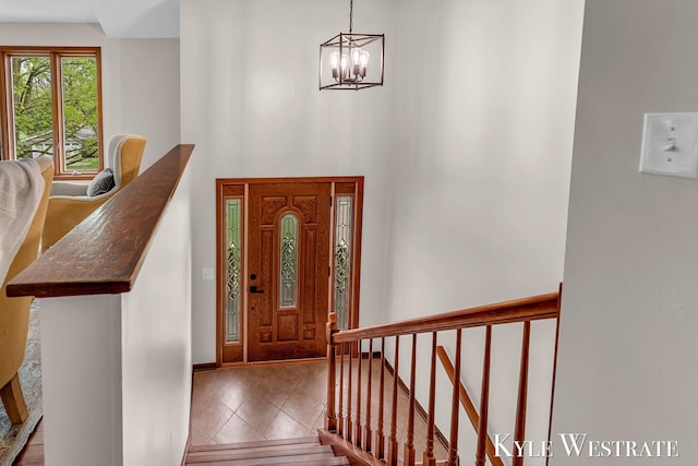 entryway with a chandelier, tile patterned flooring, a high ceiling, and stairs