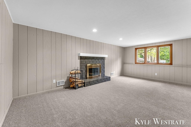 carpeted living room with a brick fireplace, recessed lighting, and wooden walls