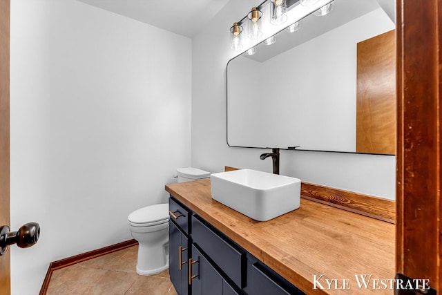 bathroom with toilet, tile patterned floors, vanity, and baseboards