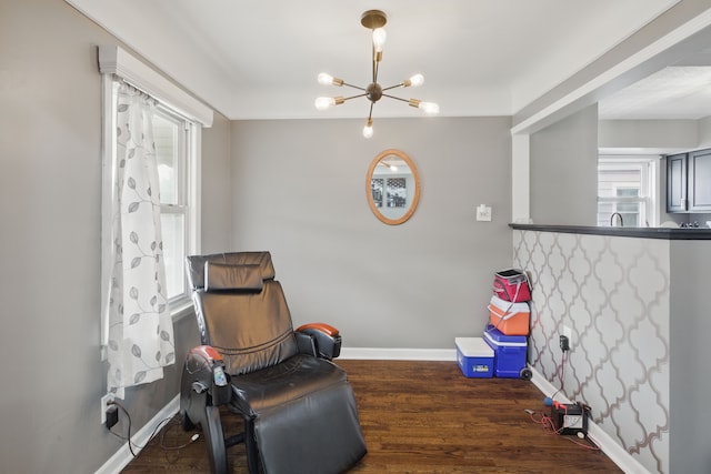 sitting room with a chandelier, baseboards, and wood finished floors
