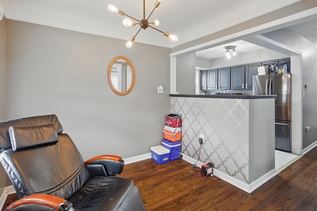 living area with baseboards, wood finished floors, and a chandelier