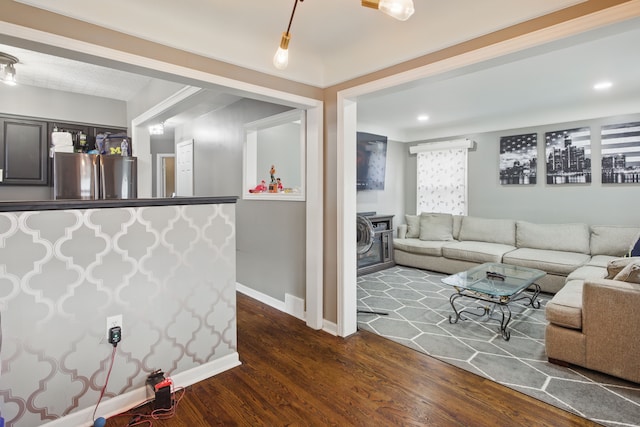 living area featuring dark wood finished floors, baseboards, and a wood stove
