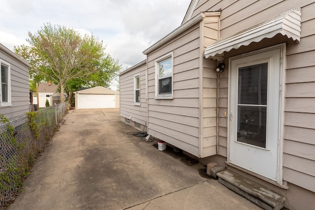 view of side of property featuring fence, a detached garage, and an outdoor structure