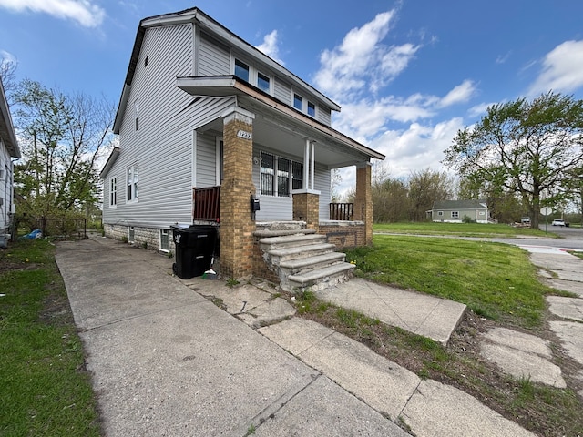 17233 Fenelon St, Hamtramck, MI 48212 - view of front of home with a porch, a front yard, and brick siding