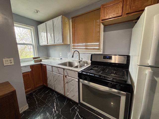 17233 Fenelon St, Hamtramck, MI 48212 - kitchen featuring stainless steel gas range, a sink, freestanding refrigerator, dark marble finish floors, and light countertops