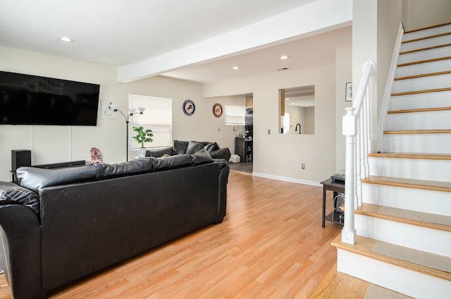 living room featuring stairs, light wood finished floors, recessed lighting, baseboards, and beam ceiling