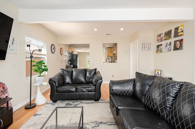 living area with recessed lighting, wood finished floors, beamed ceiling, and baseboards