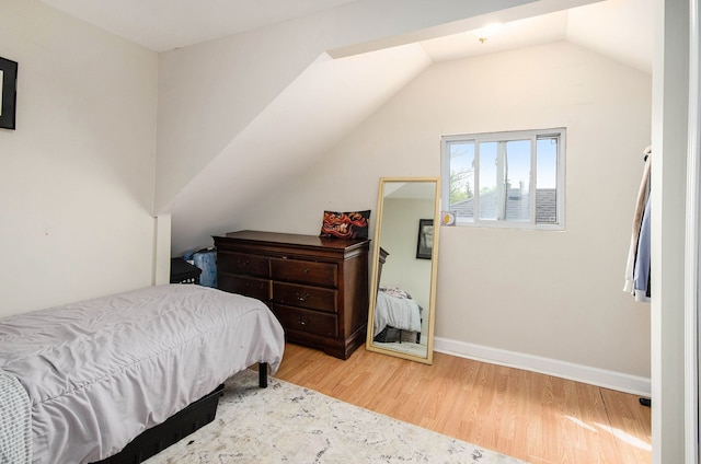 bedroom with wood finished floors, lofted ceiling, and baseboards