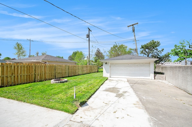 view of yard featuring a fire pit, a detached garage, and an outdoor structure