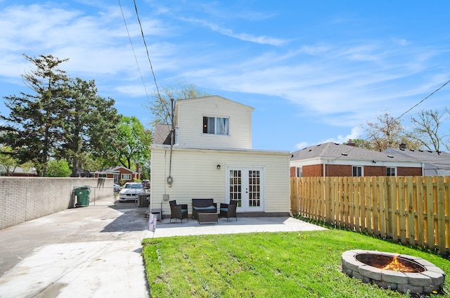 back of house with french doors, an outdoor fire pit, concrete driveway, and a patio area