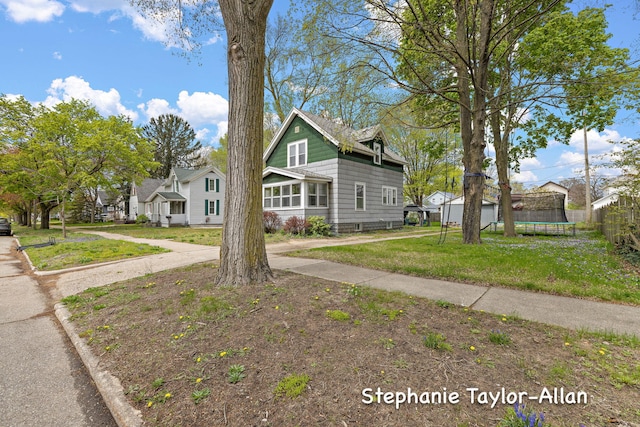bungalow-style home with a trampoline and a front yard