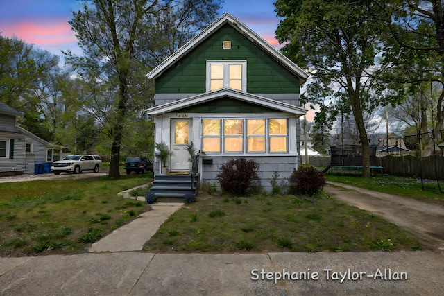 shotgun-style home with a trampoline, fence, and entry steps