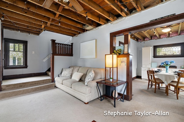 living room featuring light carpet, stairs, and baseboards