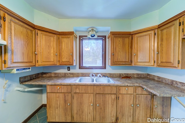 kitchen featuring a sink, brown cabinetry, and baseboards