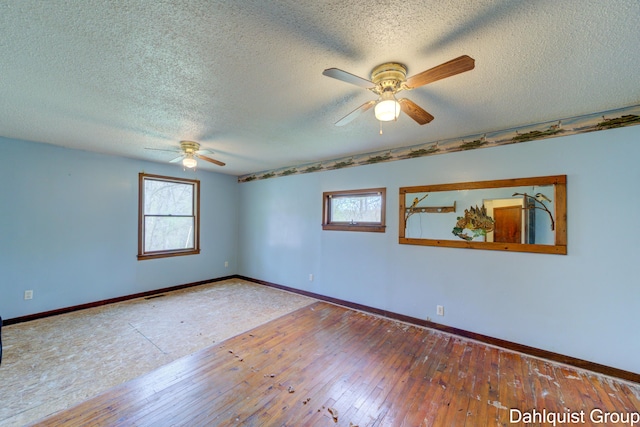unfurnished room with ceiling fan, plenty of natural light, baseboards, and a textured ceiling