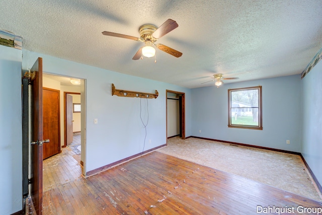 unfurnished bedroom featuring a textured ceiling, hardwood / wood-style floors, a closet, baseboards, and a ceiling fan