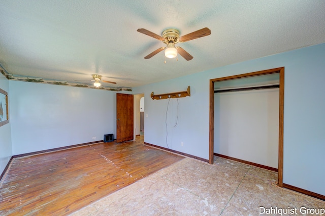 unfurnished bedroom with baseboards, ceiling fan, a closet, a textured ceiling, and arched walkways