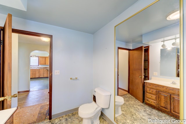 bathroom featuring toilet, vanity, ensuite bathroom, and baseboards