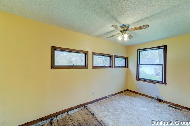 spare room featuring ceiling fan, a textured ceiling, and baseboards