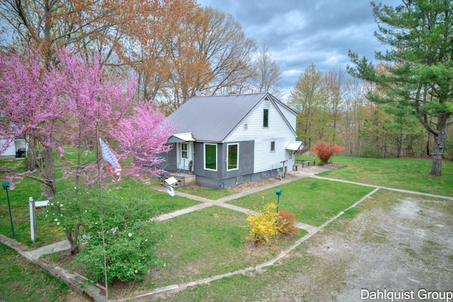 view of property exterior with metal roof and a lawn