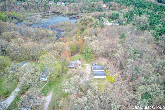 aerial view of property and surrounding area with a heavily wooded area and a large body of water