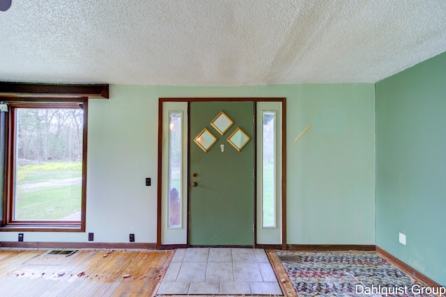 foyer entrance with a textured ceiling and baseboards