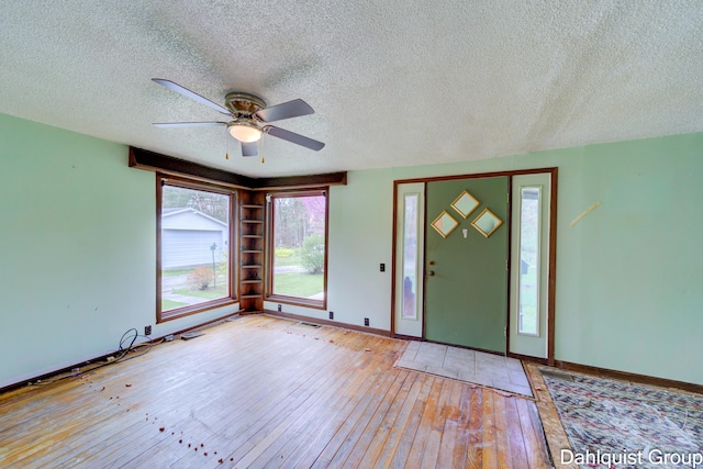 foyer with a textured ceiling, light wood-style floors, a ceiling fan, and baseboards