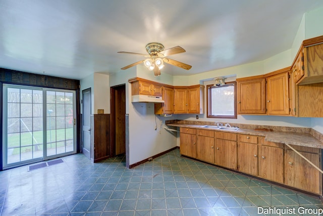 kitchen featuring under cabinet range hood, ceiling fan, a sink, brown cabinetry, and baseboards