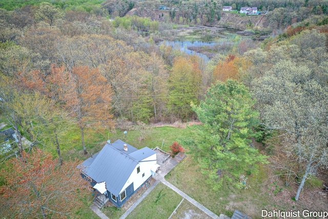 aerial view of property and surrounding area featuring a heavily wooded area and a large body of water