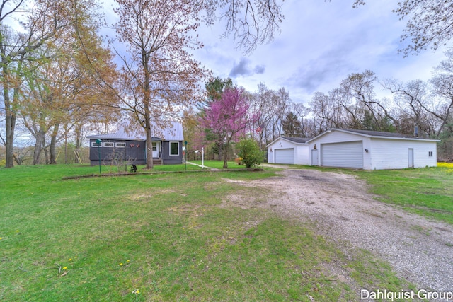 view of green lawn featuring a garage, an outdoor structure, and dirt driveway