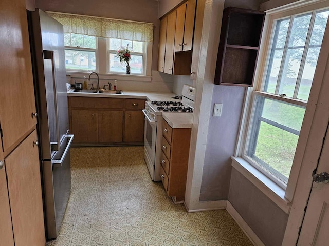 335 Emory St, Howard City, MI 49329 - kitchen featuring white gas range oven, a sink, brown cabinetry, light countertops, and high end refrigerator
