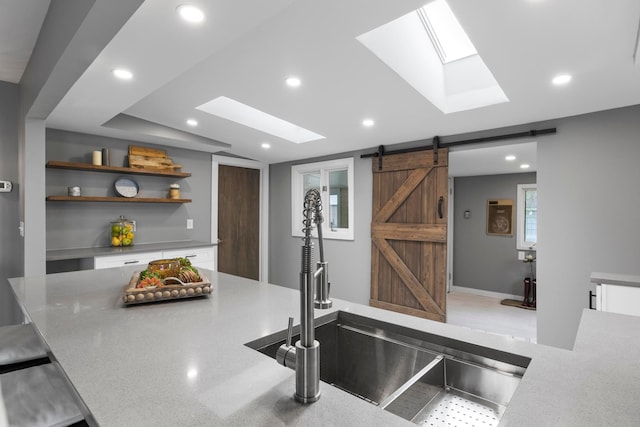 kitchen with a skylight, a barn door, white cabinetry, open shelves, and recessed lighting