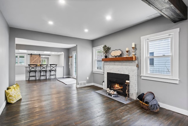 living room featuring baseboards, wood finished floors, a fireplace, and recessed lighting