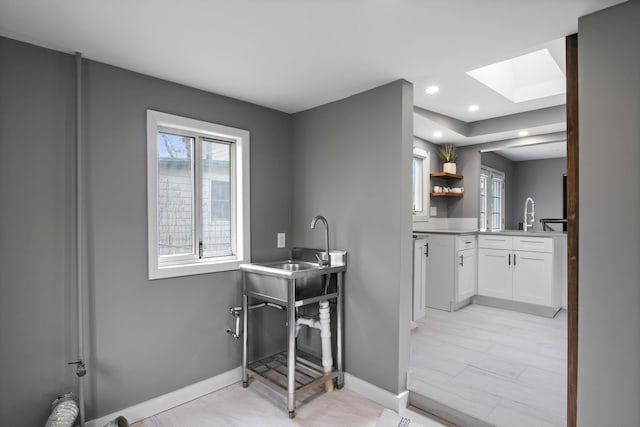 bathroom featuring a skylight, baseboards, vanity, and recessed lighting